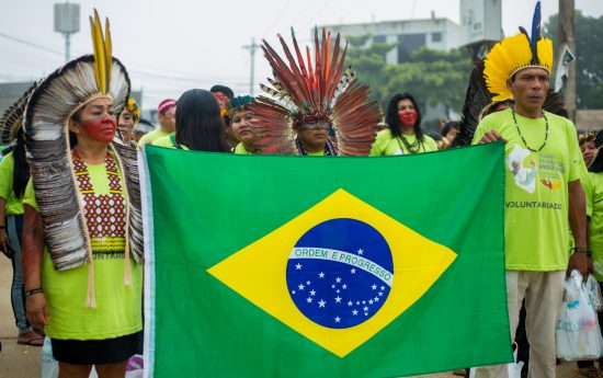 Indígenas levam bandeira do Brasil no caminho ao Coliseu Madre de Dios, onde participaram de encontro com o Papa. Foto: Tiago Miotto/Cimi