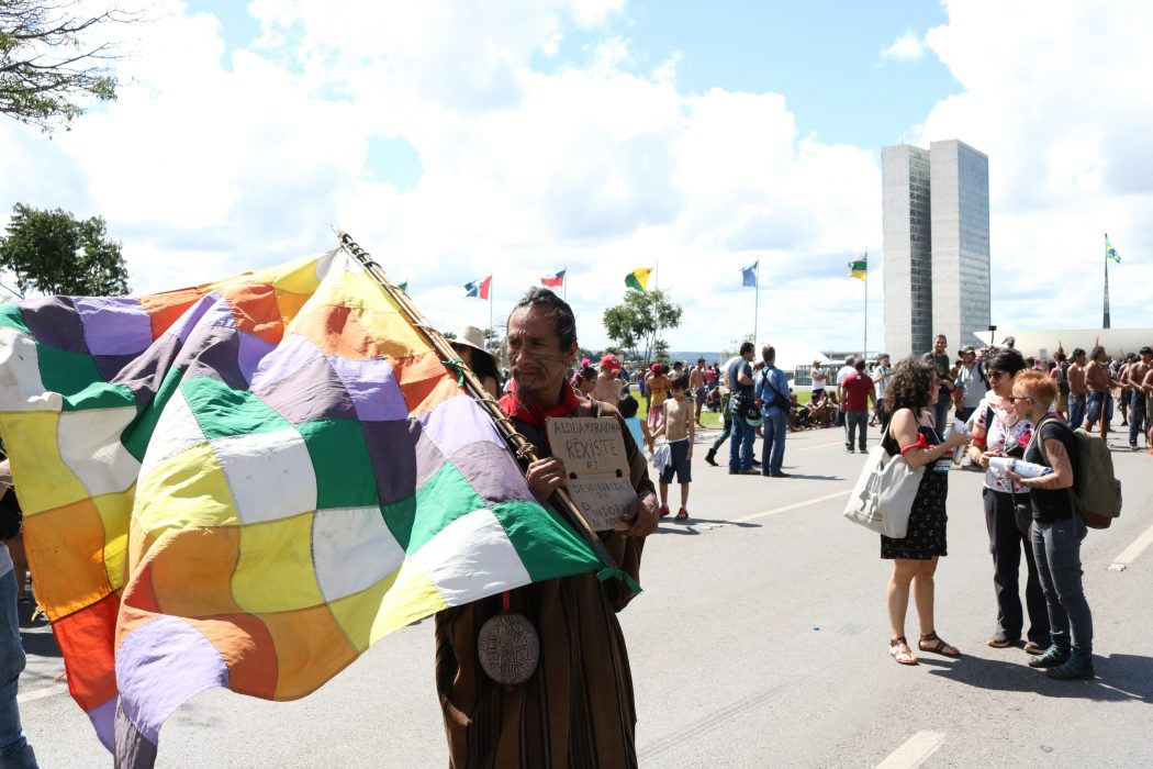 Durante a marcha do último dia do ATL 2019, indígena carrega a Whipala, bandeira que simboliza a união dos povos da América Latina. Foto por Verônica Holanda/Cimi