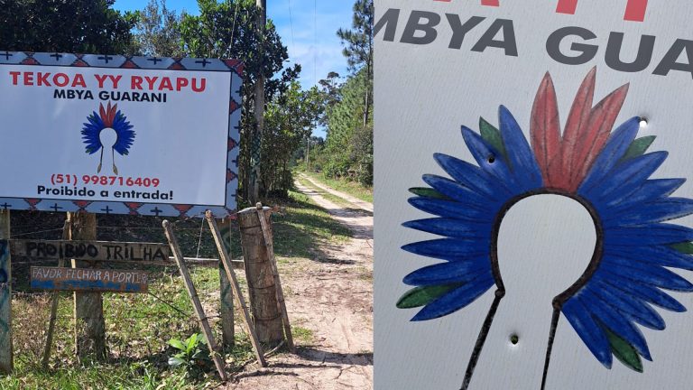 Placa na entrada da comunidade Tekoa Yy Ryapu, em Palmares do Sul (RS), é alvejada a tiros